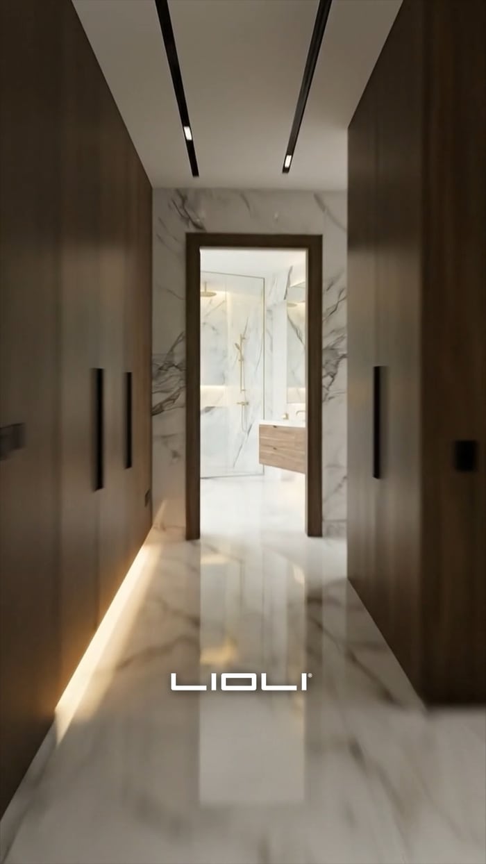 Pasillo revestido en porcelanato de gran formato con iluminación rasante