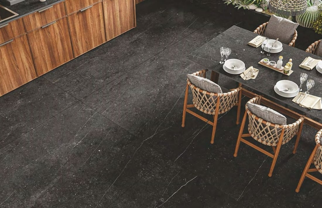 Terraza exterior con piso de porcelanato negro de gran formato y comedor de jardín